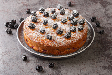Summer breakfast blackberry pie with fresh berries on top and powdered sugar close-up in a plate on the table. horizontal