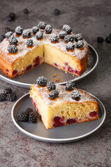 Delicious homemade sliced cake with fresh blackberries close-up in a plate on the table. Vertical