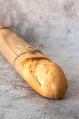 Baguette bread, french stick, wrapped in brown paper tied with string.  Recycle packaging concept