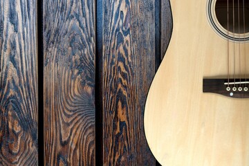 Obraz premium Acoustic guitar resting against a wall background