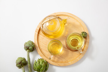 Artichokes teapot in a wooden tray with fresh artichoke. Artichoke tea has the ability to fight...