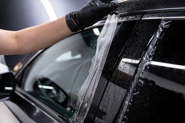 employee of the car detailing studio protects the car body with a colorless protective film