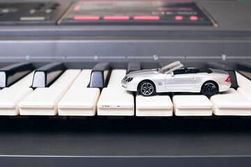 Gray toy car on piano keys closeup