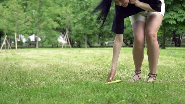 Legs of a brunette girl playing frisbee in the park on a summer day 