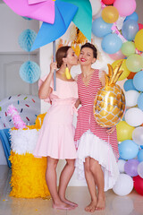 Party and celebration. Two happy smiling young women having fun together at home decorated with air baloons.