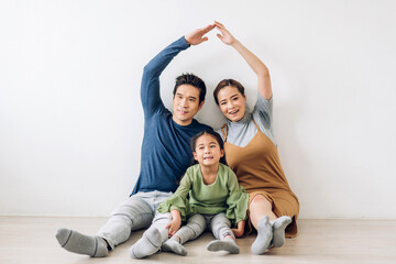 Fototapeta na wymiar portrait enjoy happy smiling love asian family father and mother with young parents little asian girl sitting and making roof house with hands arms over head in new home