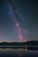The Milky Way over the lake Schluchsee and the Black Forest in Germany.