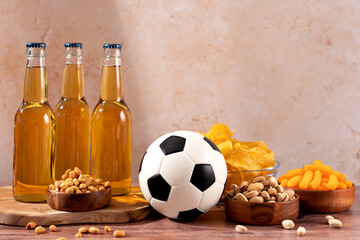 Beer and snack on wooden table with football ball, football game night food