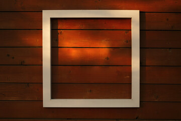 Wooden red background for an inscription with a white frame and spots of sunlight. copy space.