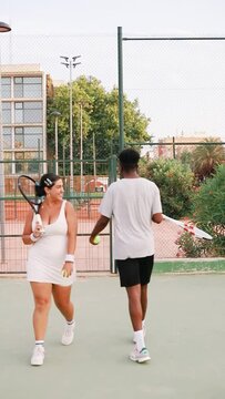 Couple walking on the tennis open-air court and smiling