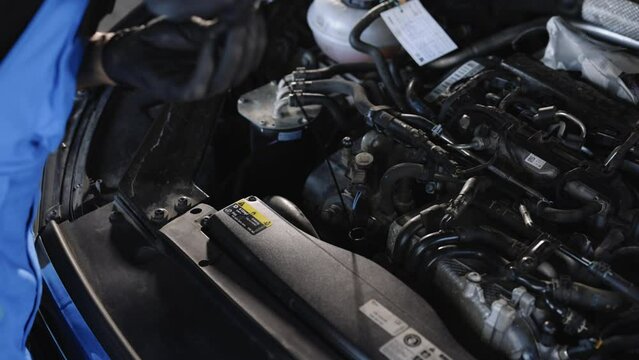The car mechanic is checking the engine oil level. Overheating of car engine. Motor with open hood. Checking the engine oil car maintenance Remove the dipstick to view the engine oil level