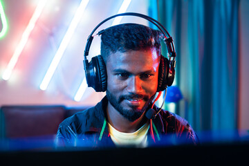 close up head shot of professional gamer talking on headphone while playing live video game on computer at home - concept of entertainment, hobbies and tournament. © WESTOCK