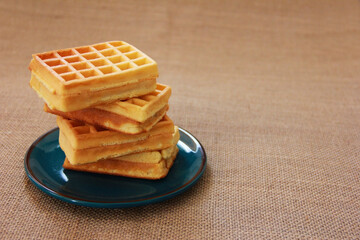 sweet fluted belgian waffles in a blue plate on a brown background