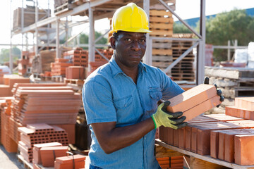 Portrait african american worker lays bricks in an open air warehouse