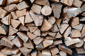 Fototapeta premium View of a Stack of Firewood. Background of Dry Chopped Logs in a Woodpile. Natural Texture. Preparation of Firewood for the Cold Winter
