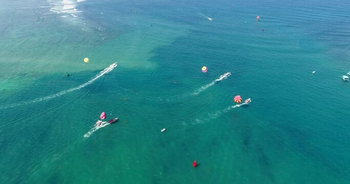 Aerial shot of parasailing boats going over turquoise water