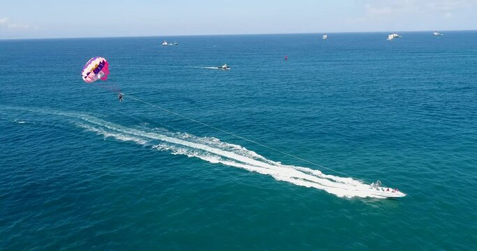 Aerial shot of a parasailing boat going over turquoise water