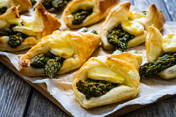 Baked puff pastry with asparagus and cheese on baking paper on wooden table