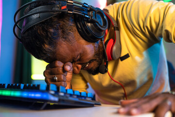 close up shot of Gamer with headphones sad due to loss while playing video game on computer at home...