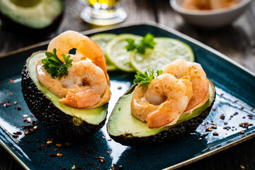 Avocado with fried prawns on and cocktail sauce on wooden background
