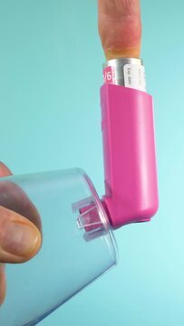 Vertical video social media format – A man’s hands holding an asthma inhaler canister, while pressing the attached pressurized container, to activate a dose of medicine.