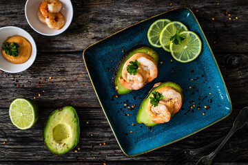 Avocado with fried prawns on and cocktail sauce on wooden background

