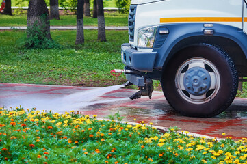 A special machine washes city paths and roads with water. Side view. No people. Selective focus