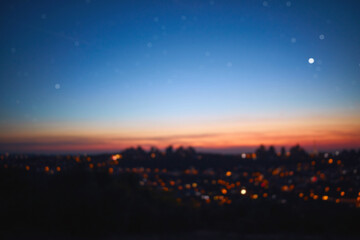 Out of focus image of crescent young Moon and planets on colorful sky.