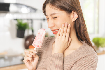 Face expression suffering from sensitive teeth and cold, asian young woman, girl hand touching her cheek, feeling hurt, pain eating ice cream, lolly. Toothache molar tooth at home, dental problem.