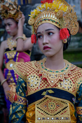Two young Bali smiling girls make -up dressed in traditional colored costumes inside in the temple.