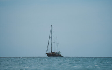 Old school ship in the ocean, blue cloudless sky.