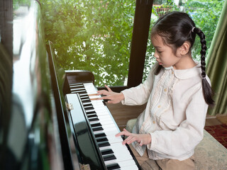 Asian little girl practice play piano in house.