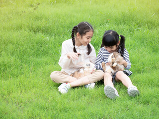 Two little girl holding rabbits and smiling on green grass in nature background. Children and rabbits in field.