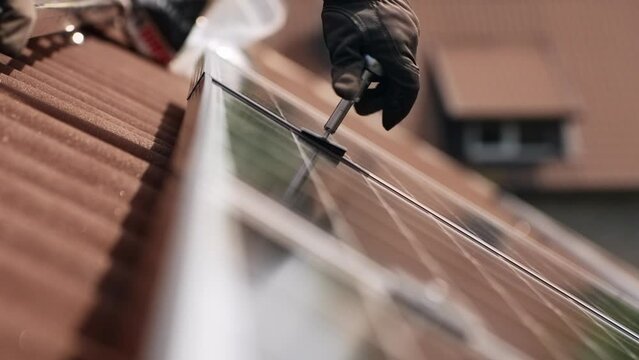 Hand of person using modern rachet wrench to fix solar panel to house roof