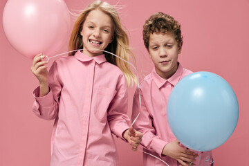 Fototapeta premium horizontal portrait of happy children in pink clothes playing with pink and blue balloons