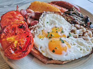 English Big Breakfast with sunny fried eggs, sausage, bacon, tomatos, hash brown, mushroom