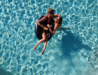 lgbt couple drinking and smiling  in swimming pool