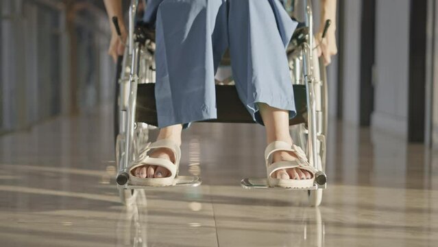 Female patient in wheelchair in hospital hallway,Low angle view,Slow motion