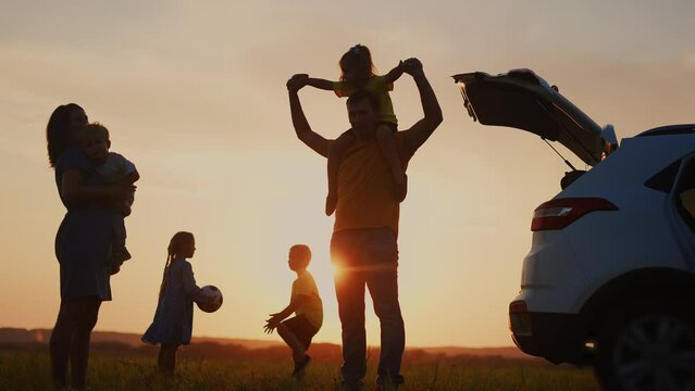 happy family. children stand together next to the car silhouette of in the park. travel family dream concept. happy family sunset standing with sunlight, back watching the journey in the park