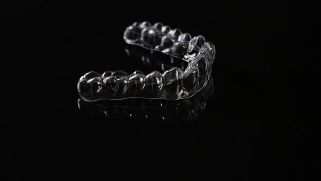 Invisible orthodontics cosmetic brackets on black background. Tooth aligners, for beautiful smile.