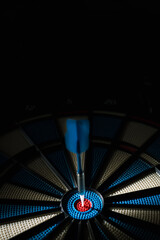 A dart hitting the center of target with copy space in dramatic light and shadow. Bullseye target or a dart dashboard for financial business planning and targeting with winner goal concept - 522221659