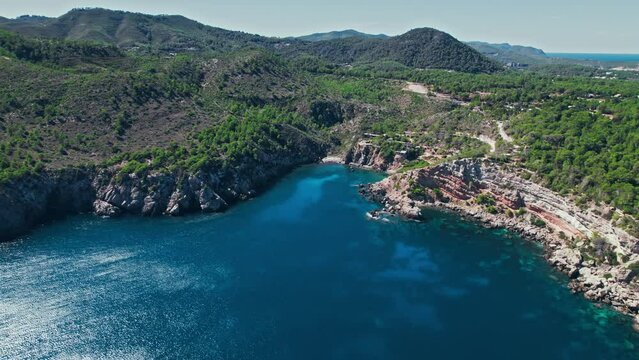 Drone view of corals in turquoise transparent mediterranean sea in Ibiza, Spain. Rocky seashore with blue water and tropical nature on the Balearic islands.