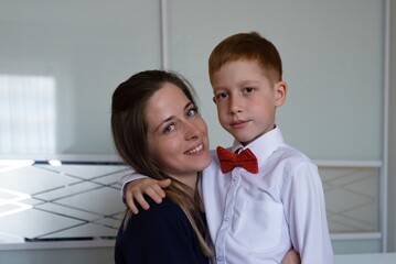 Family holiday mom helps son smartly dressed red-haired boy at graduation in kindergarten, life...