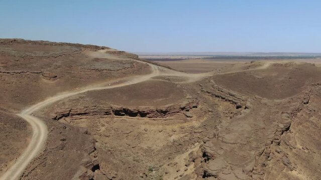 Dirt road over Gara Medouar mountain at Errachidia near Sijilmasa in Morocco, Africa. Aerial drone flyover