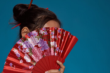 Girl covering face with traditional handheld fan