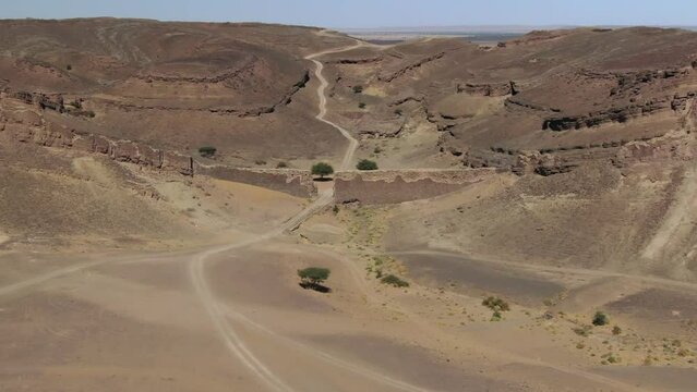 Ancient fortification wall at entrance of African Gara Medouar rock formation, Errachidia in Morocco. Drone pov