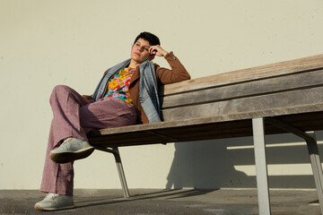 full length shot of a overwhelmed short-haired woman sitting on a bench of a public place watching something far