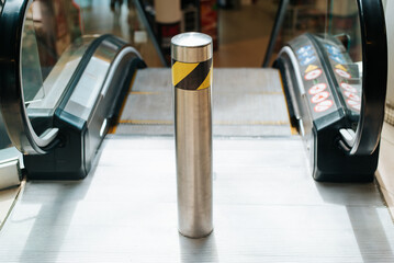 Close-up of an escalator in a shopping or business center, selective focus on a pole.