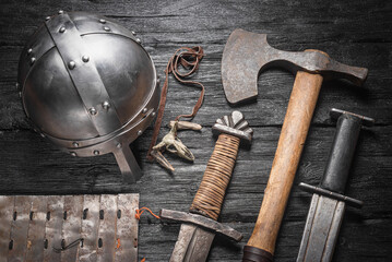 Ancient battle sword, axe and warrior helmet and armor on the wooden table background with copy...