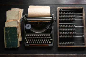 Typewriter, books and retro abacus on old vintage flat lay table background. Education concept...